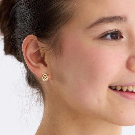 Close-up of a person wearing a gold earring with a white background