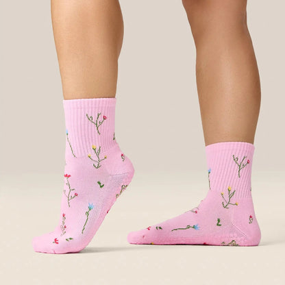 Pink socks with floral patterns worn by a person on a beige background