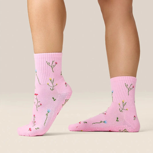 Pink socks with floral patterns worn by a person on a beige background