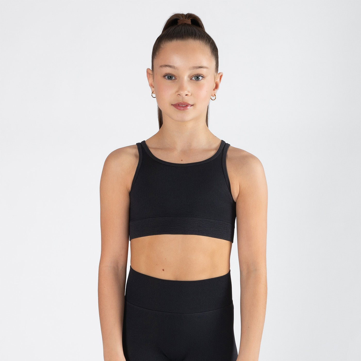 Person wearing a black sports bra and shorts on a white background
