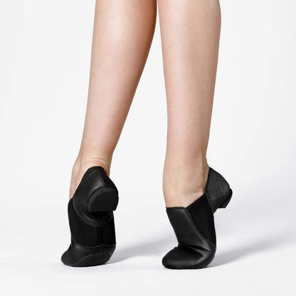 Black jazz shoes worn on feet against a white background