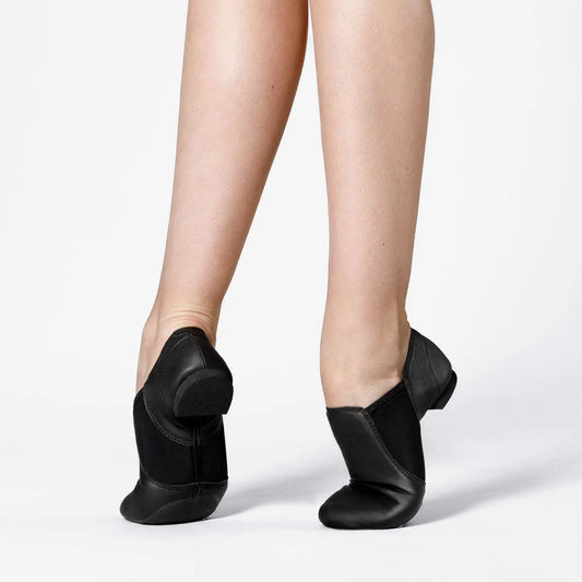 Black jazz shoes worn on feet against a white background