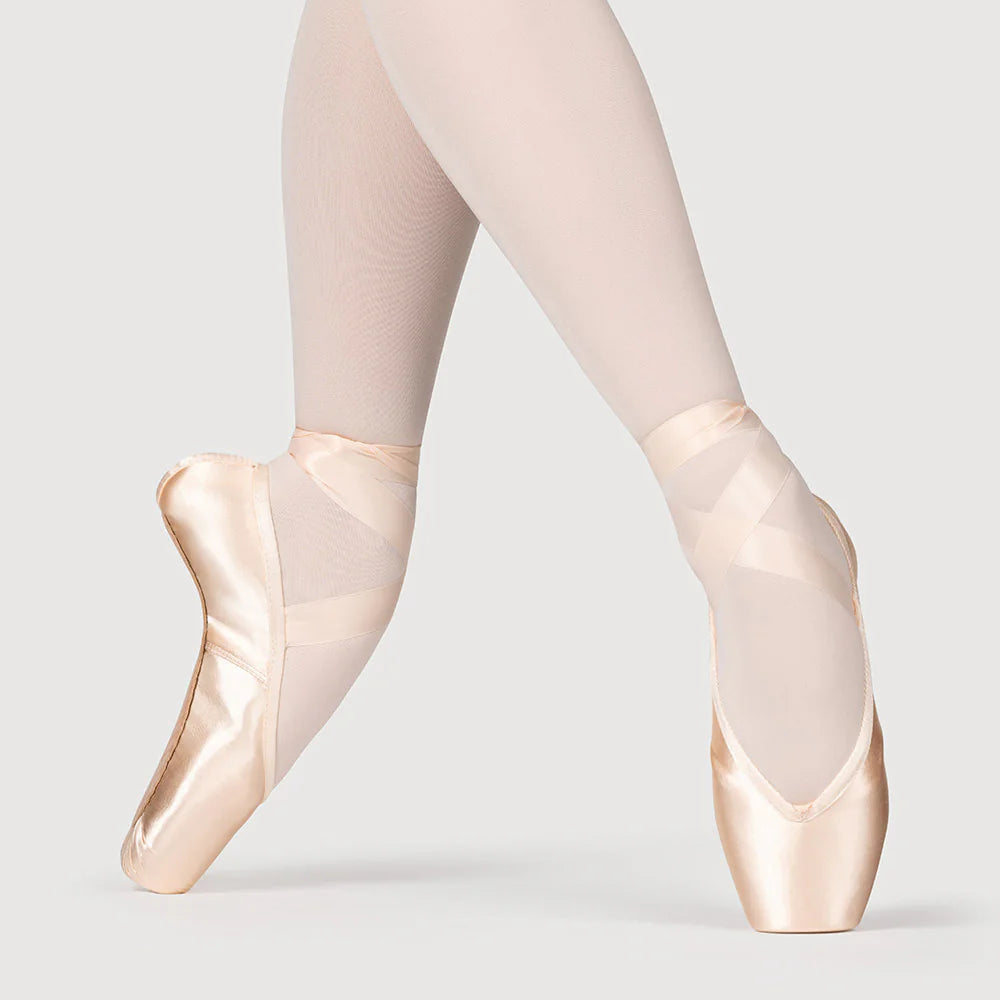 Ballet shoes worn with tights on a plain background