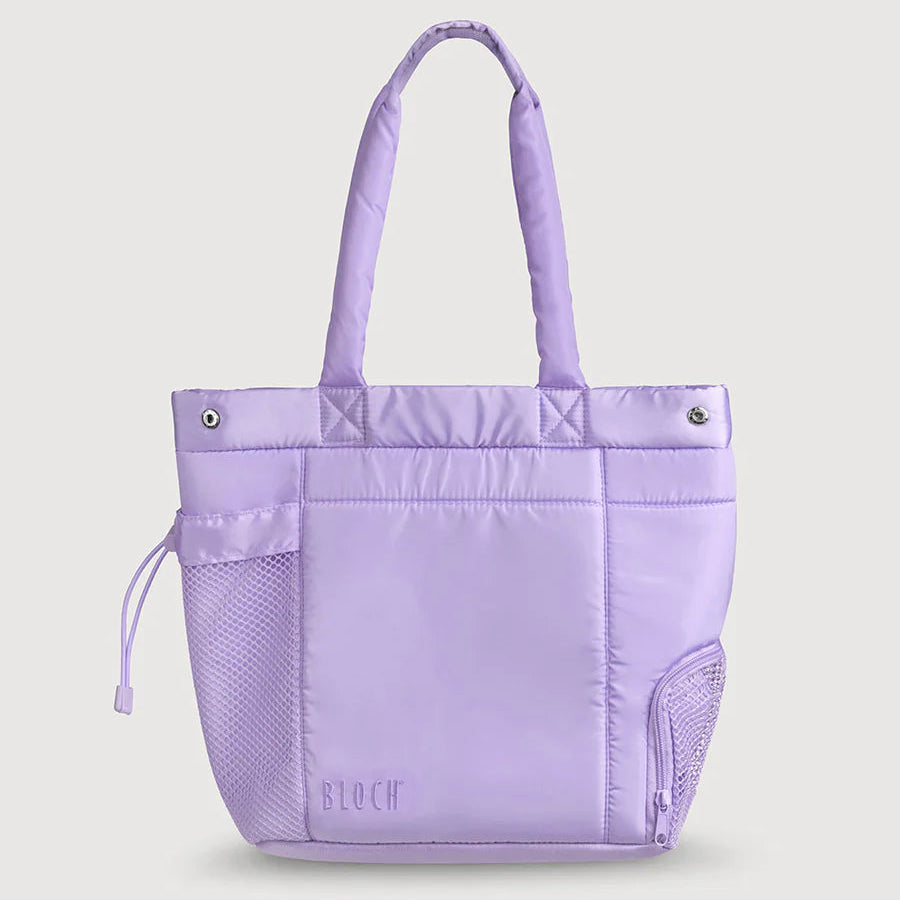 A light purple/lavender tote bag with dual top handles, a front zip pocket, mesh side pockets, and a subtle 'BLOOM' logo near the bottom, shown on a solid light gray background.