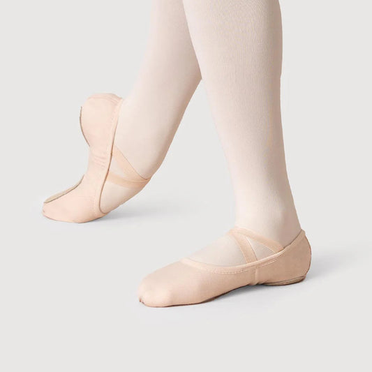 Ballet shoes worn with tights on a plain background