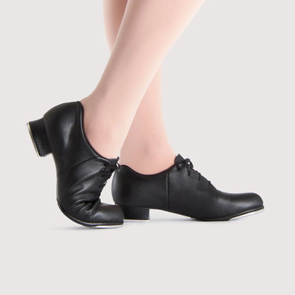Black tap shoes worn by a person on a light gray background
